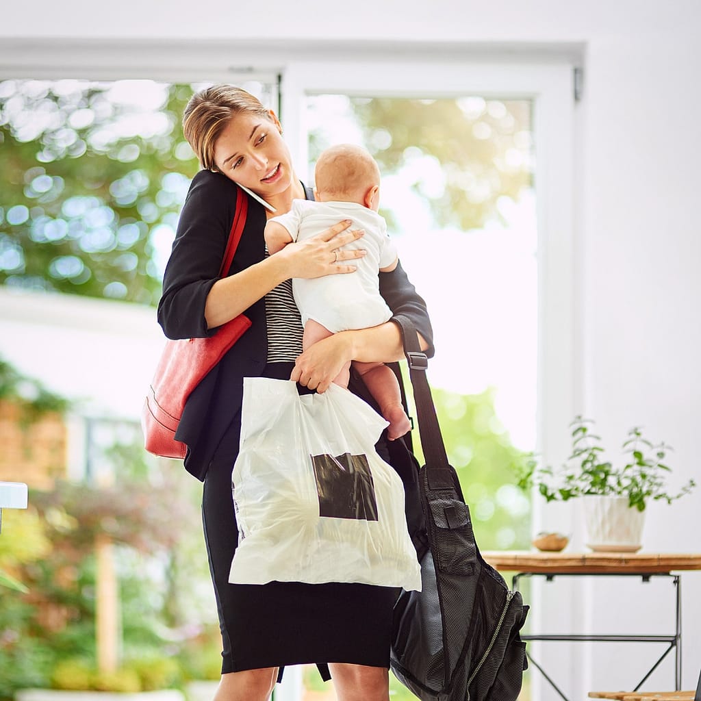 Working parent multitasking with baby phone and laptop experiencing mom brain forgetfulness and overwhelm